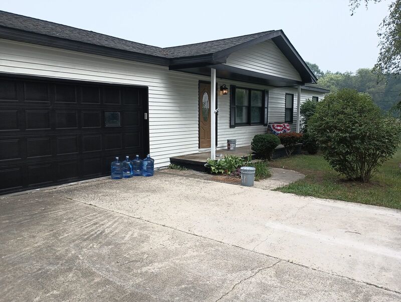 Finished garage door and entry, black door and trim against white siding